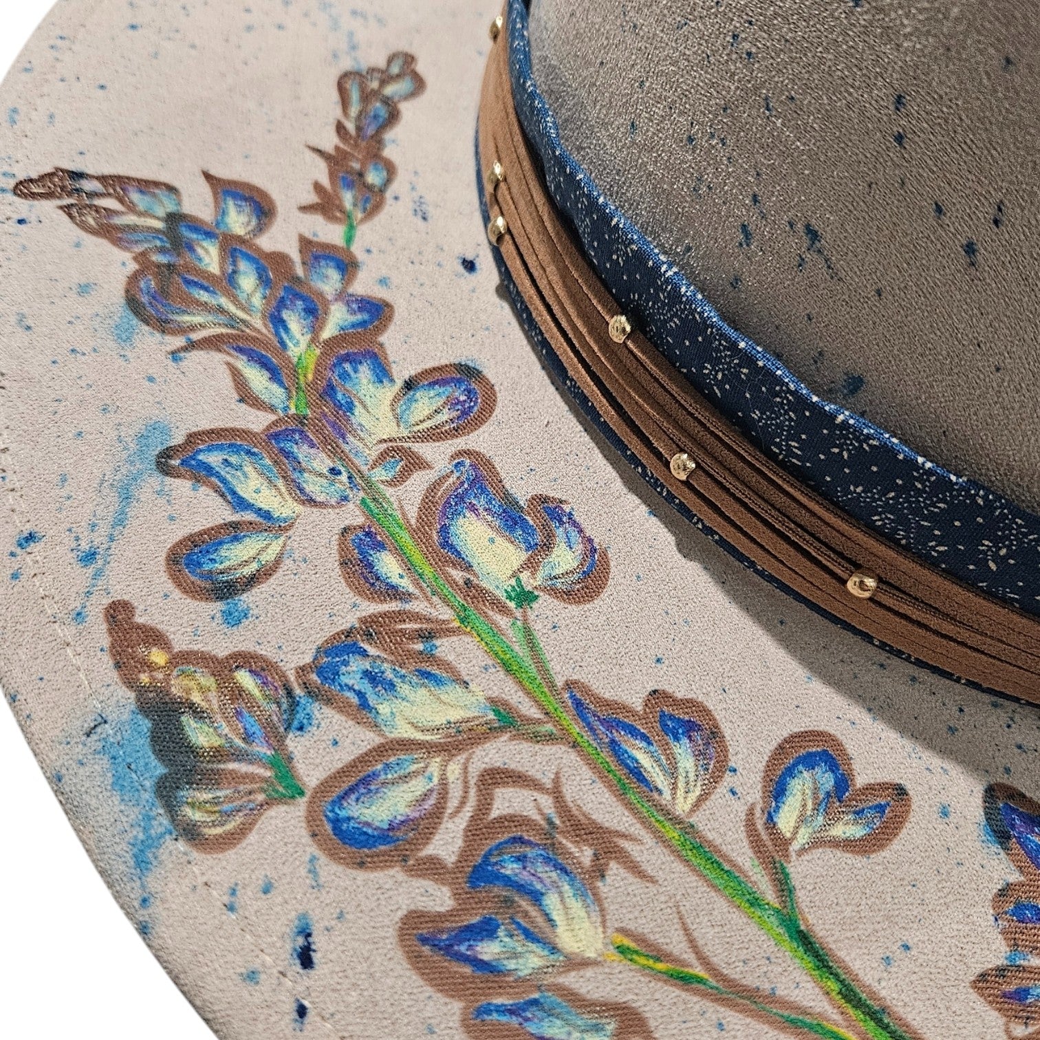 Close-up detail of hand-painted bluebonnets on left side of rancher hat on white background