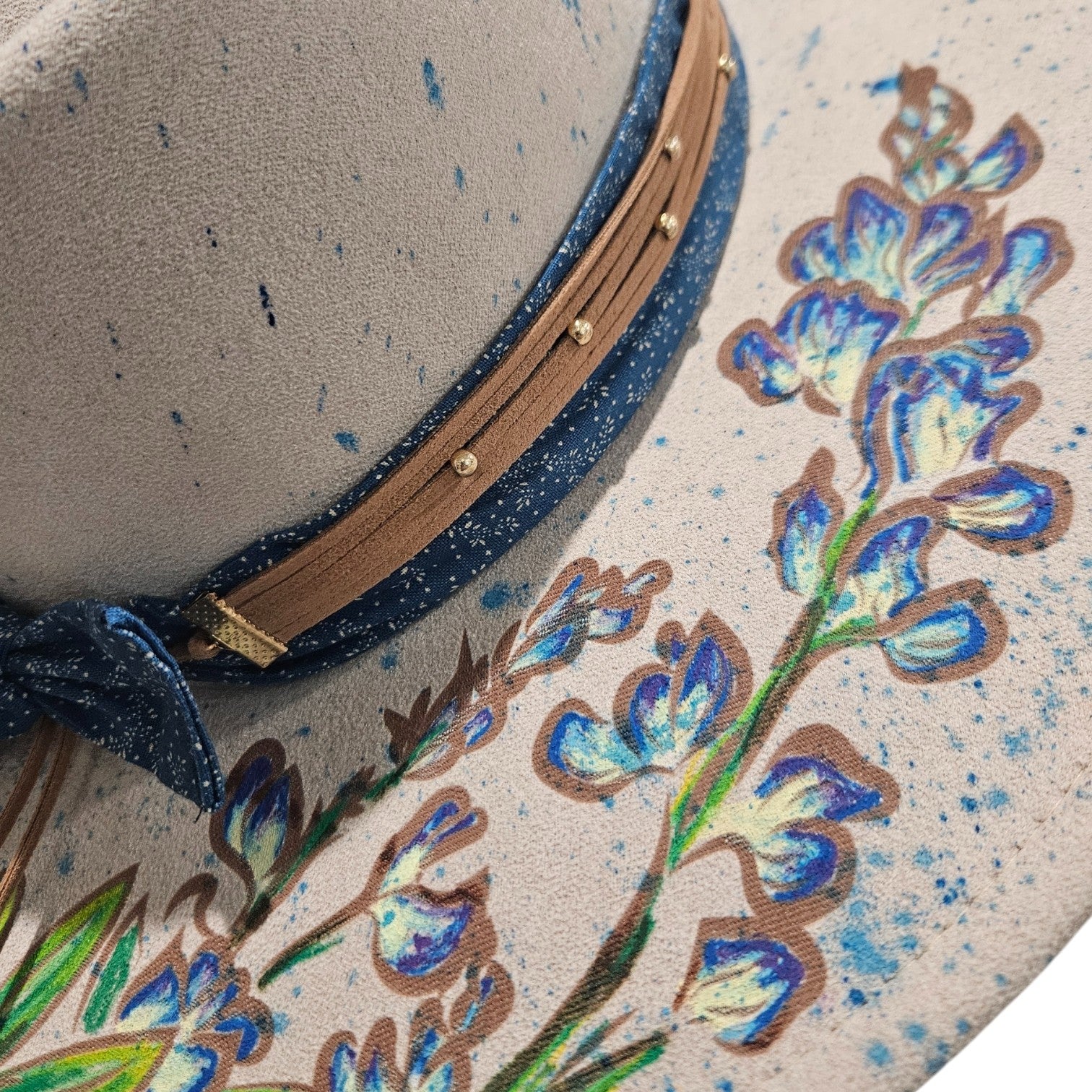 Close-up detail of hand-painted bluebonnets on right side of rancher hat on white background