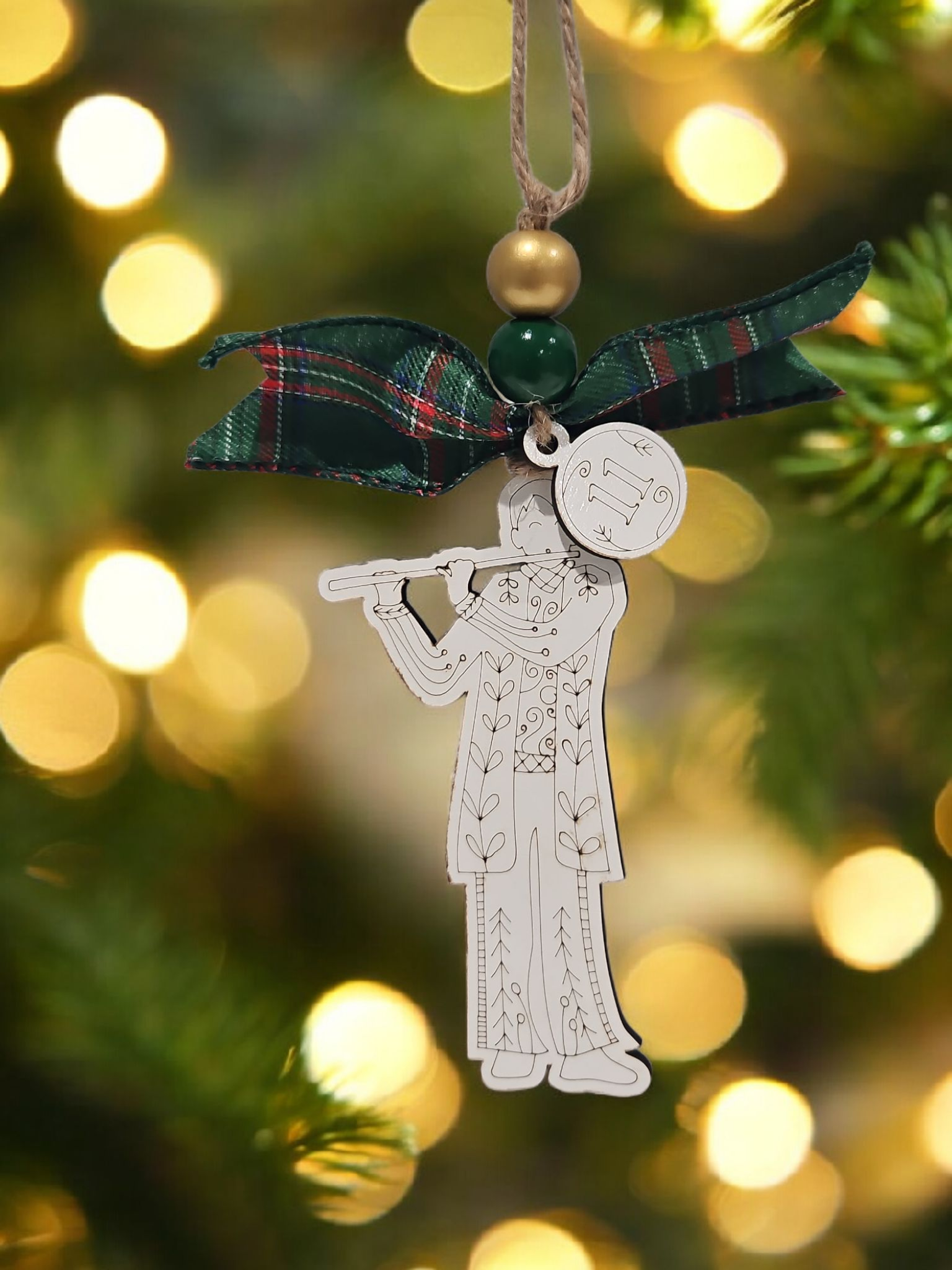 Day 11 eleven pipers piping engraved white wood ornament hanging on Christmas tree with bow and bead.