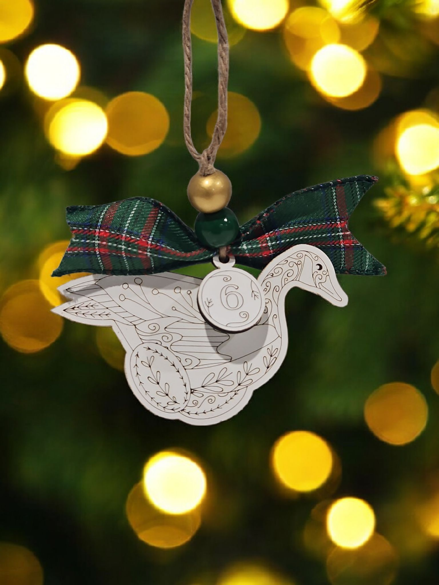 Day 6 six geese a-laying engraved white wood ornament hanging on Christmas tree with bow and bead.