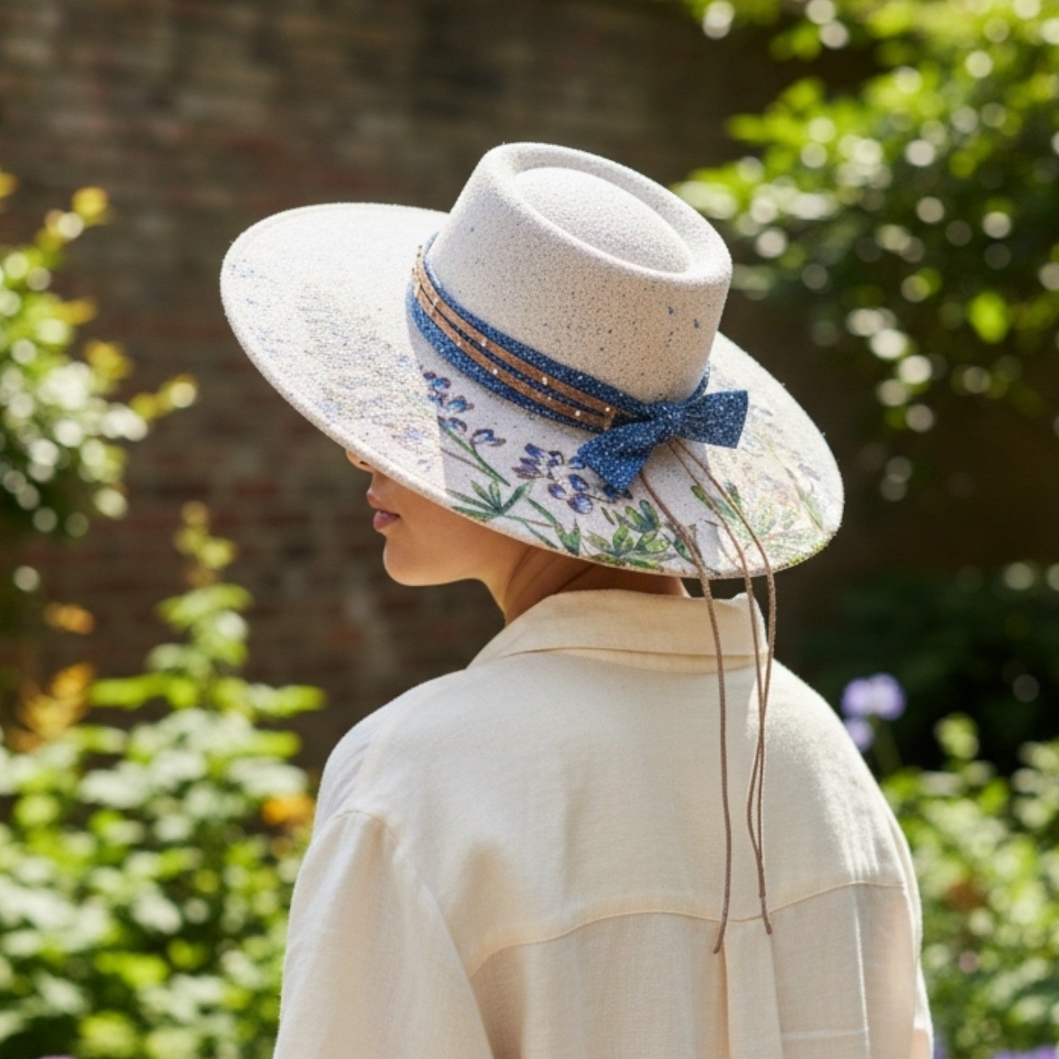 Woman wearing hand-painted bluebonnet floral rancher round top hat