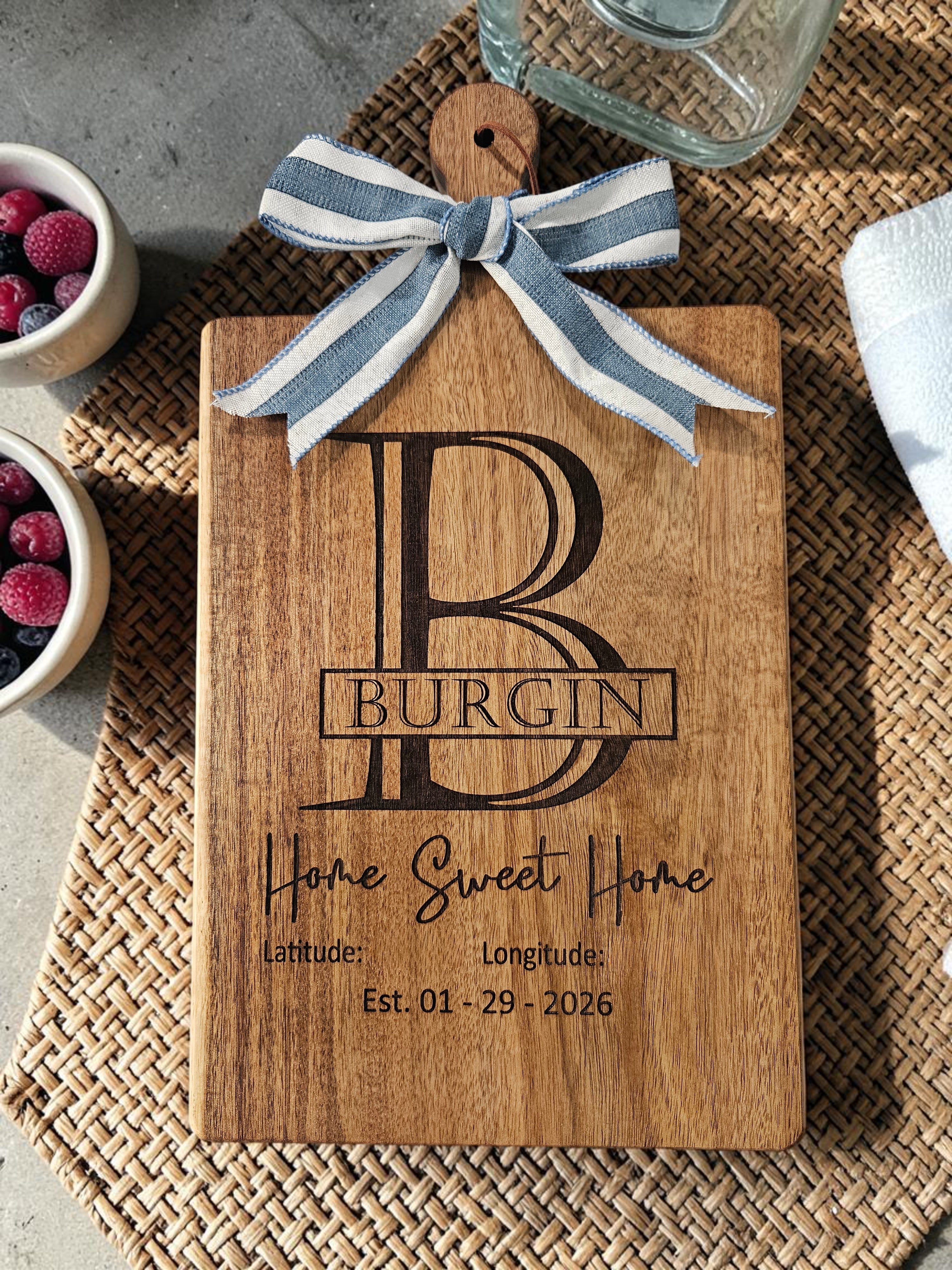Custom laser-engraved acacia wood cutting board personalized with a monogram and home coordinates handcrafted by Ratchet Arts Designs in Texas